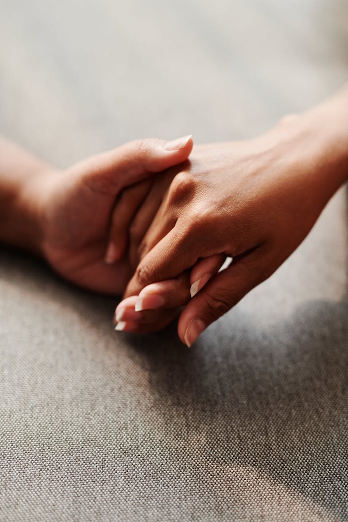 services-03 A close-up of two hands clasped together on a grey textile background, symbolizing unity.